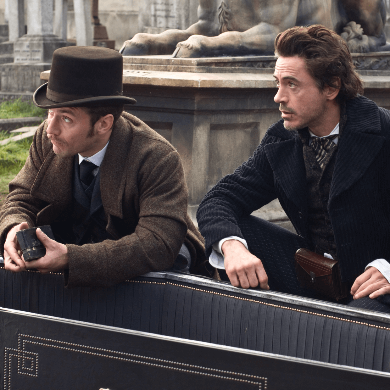Sherlock Holmes and Watson sitting near a casket